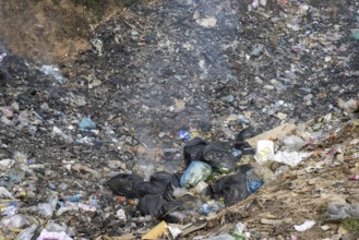 Coking rubbish dump, rubbish pit with waste and plastic rubbish, karst landscape near Vang Vieng,