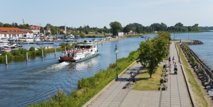 River promenade with people and a ship on the water of a coastal town, Gizycko,