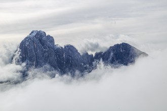 Massive mountain peaks, shrouded in thick clouds and fog, rise up majestically