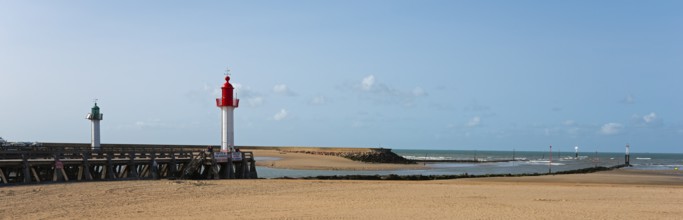 Extensive beach with a green and a red lighthouse, blue sky and calm sea, green lighthouse in