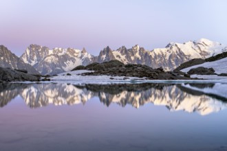 Evening mood with pink evening sky, mountain landscape at sunset, water reflection in Lac Blanc,