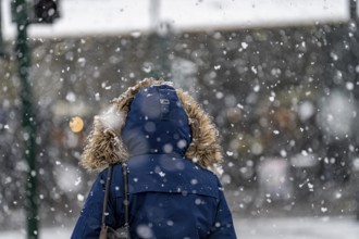 Winter weather, heavy snowfall, city centre traffic, passers-by in the snow, person with fur hood