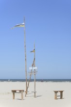 Pile dwelling on the extensive sandy beach, wooden piles with Juist flag, wooden planks with