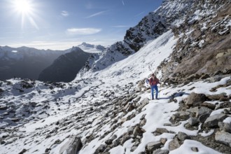 Mountaineer on a hiking trail with snow, on the ascent to Ramoljoch, behind mountain Ramolkogel,