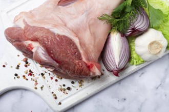 Raw pork knuckle, on a wooden chopping board, with spices, close-up, top view, no people