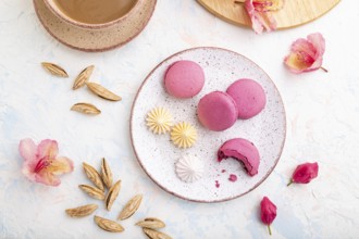 Purple macarons or macaroons cakes with cup of coffee on a white concrete background decorated with