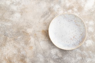 Empty blue and gold ceramic plate on brown concrete background. Top view, copy space, flat lay