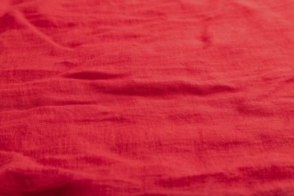 Fragment of smooth red linen tissue. Top view, flat lay, natural textile background and texture