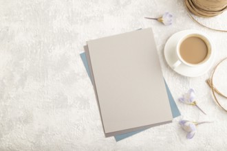 Gray paper sheet mockup with spring snowdrop crocus flowers and cup of coffee on gray concrete