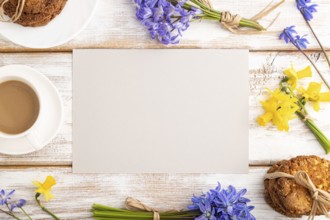 Gray paper sheet with oatmeal cookies, spring snowdrop flowers bluebells, narcissus and cup of