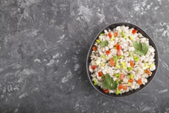 Pearl barley porridge with vegetables in blue ceramic bowl on a black concrete background. Top