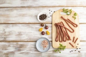 Traditional polish smoked pork sausage kabanos on cutting board with salt and pepper on white