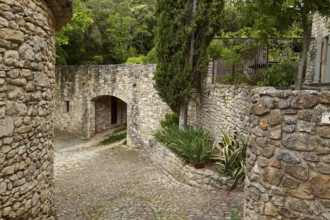 Paths and walls made of natural stone with an archway and Mediterranean gardens in La