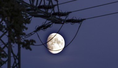 The rising moon can be seen behind an electricity pylon, Schönefeld, 06.10.2022