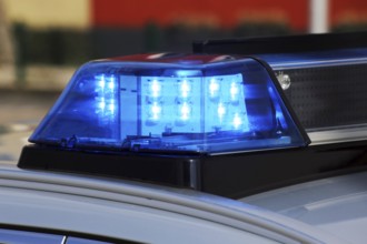 Symbolic image: Close-up of a police car with blue lights at night