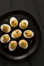 Boiled eggs stuffed with yolk with mayonnaise, on a black plate, selective focus, blurry, close-up,