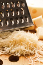 Grated cheese, Maasdam, on a cutting board, grater and cheese knife, close-up, no people