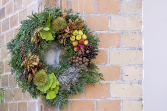 Door wreath made of natural materials in front of a house wall, Rhineland-Palatinate, Germany,