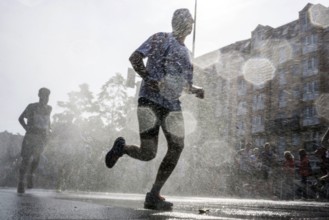 The participants of the Berlin Marathon are cooled down with a water shower in the Schöneberg