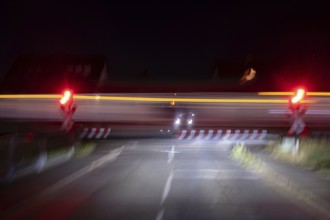 Passing train at a level crossing with barriers at night, Eckental, Middle Franconia, Bavaria,