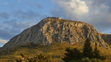 The last rays of the day illuminate a mountainous horizon with a historic castle, Archaic Castle,
