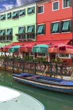 Colourful houses and colourful parasols in a restaurant on the canal, Burano, Venice, Veneto,