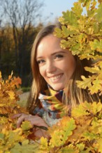 Portrait of young beautiful smiling woman, 30 years old, outdoors in forest with autumn colors in