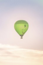 A green hot air balloon high in the sky at pastel sunrise, soft in colours, Calw, Black Forest,