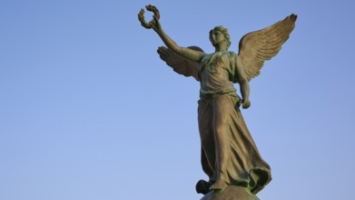 Angel statue with raised hand and outstretched wings towards the sky, harbour area, Rhodes Town,