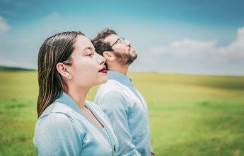 Two relaxed people breathing fresh air in the field. Young couple breathing fresh air in the field