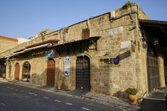 Historic stone building with various signage, traditional doors and modern use, Rhodes Old Town,