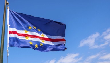 The flag of Cape Verde flutters in the wind, isolated against a blue sky