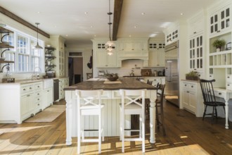 White painted maple wood antique style cabinets with tan coloured quartz countertops, island with