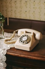 Old rotary phone sitting on a retro floral-patterned tablecloth, AI generated