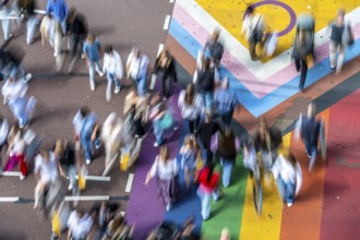 People crossing a pedestrian crossing, on a road, the road surface is colourful, in rainbow