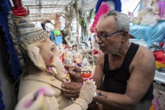 An artisan gives final touches to an idol of the elephant-headed Hindu deity Ganesha at a workshop