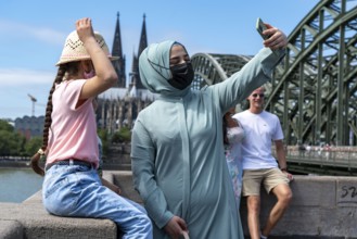 Tourists take a souvenir photo in front of Cologne Cathedral, on the Deutzer Ufer, Hohenzollern