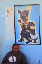 South Ethiopia, in Dimeka, local man sitting in front of a painting in a cafe, Ethiopia, Africa