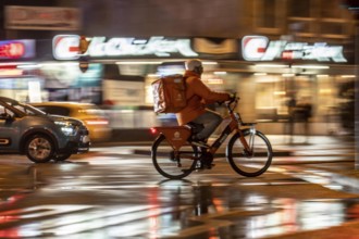 Street at the main station, Lieferando courier, cyclist, rainy weather, city centre, in the