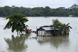 Villagers cross a flooded area on a raft, at Buraburi village in Morigaon district of Assam in