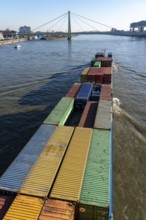 Container cargo ship on the Rhine, heading south, the crane houses in Cologne at the