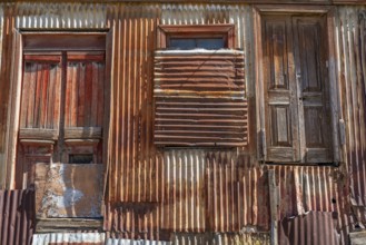 Boarded up and neglected house with a façade of rusty corrugated iron, city of Punta Arenas,