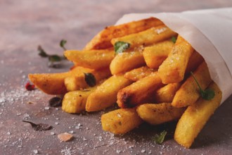 Fried French fries, in a paper bag, on an abstract background, no people, rustic