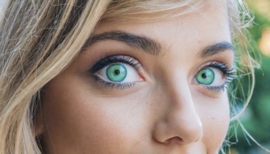 Close-up of a female face with blonde hair and intense green eyes, natural background, AI