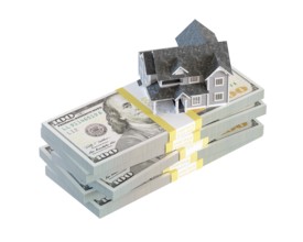 Miniature house resting on stack of thousands of dollars cash isolated on a white background