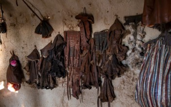 Various traditional leather aprons hanging on the wall, interior of a mud hut of the first woman in