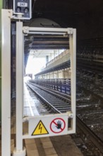 View through mirror onto railway tracks in tunnel with electricity warning sign, Vienna