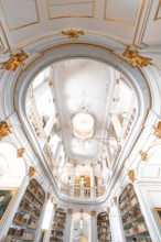 Interior view of a magnificent baroque library with richly decorated ceilings and bookshelves,