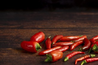 Red peppers scattered on a dark wooden surface, food photography