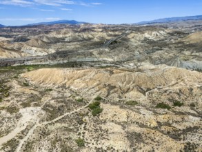 Dry desert landscape with rugged hills and a road under a clear sky, Aerial view, Tabernas Desert,